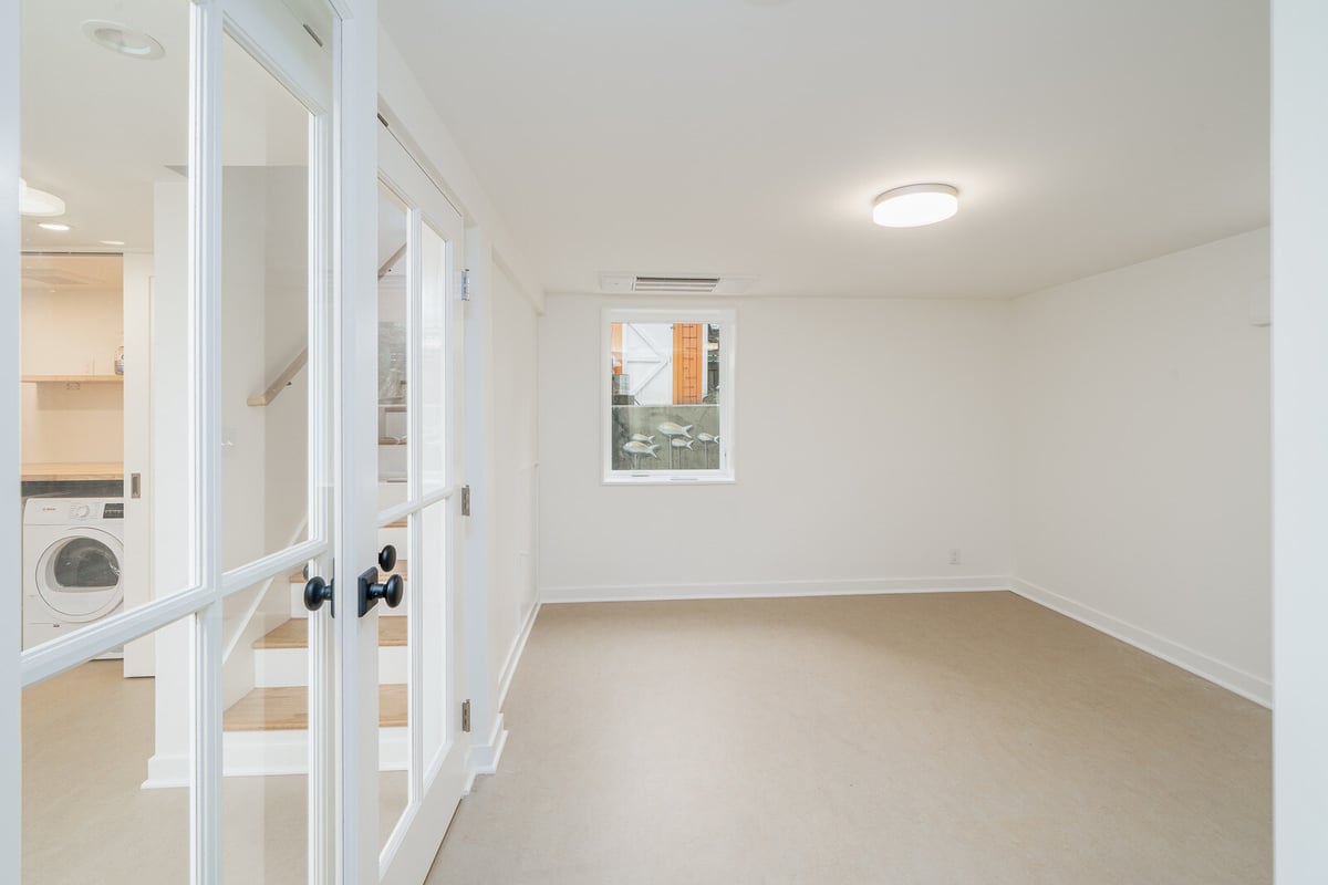 Newly renovated basement with white French doors and laundry area by CB Construction in Seattle