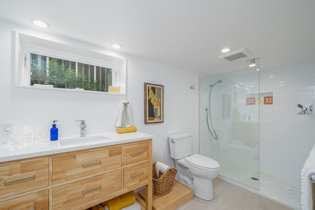 Spacious bathroom in a Seattle basement remodel by CB Construction, featuring a glass-enclosed shower and wooden vanity