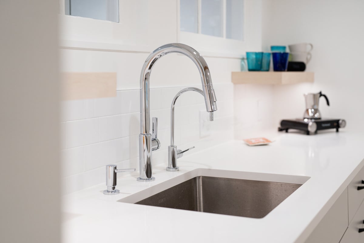 Stylish chrome faucet and countertop in a remodeled Seattle basement kitchenette by CB Construction