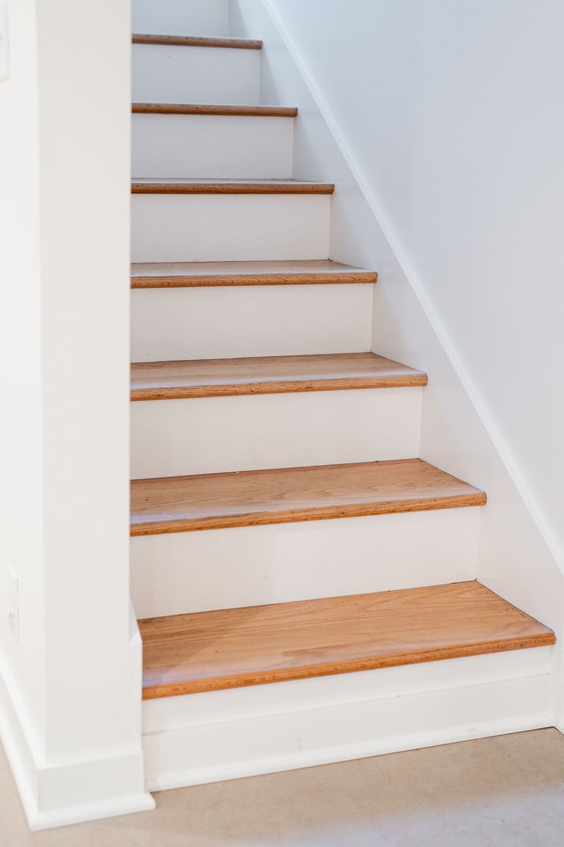 Wooden basement staircase with white walls in a Seattle home remodel by CB Construction