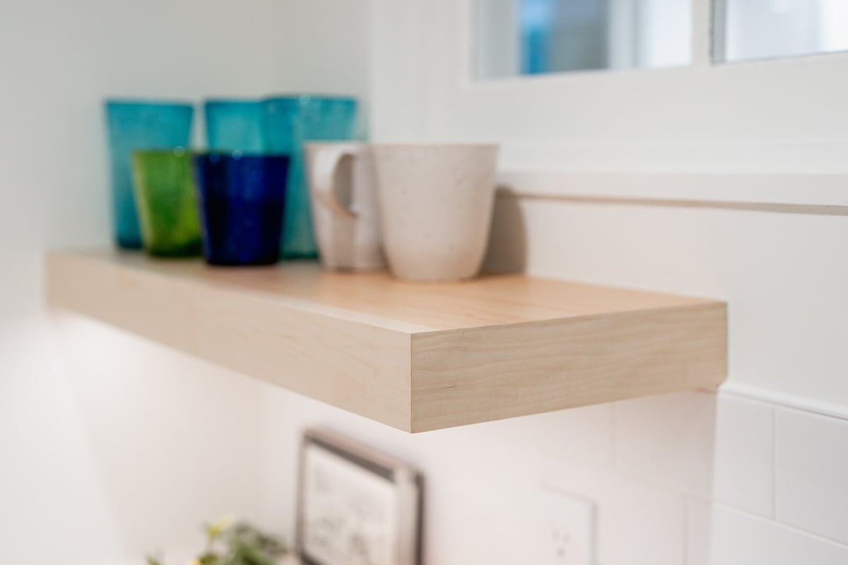 Wooden floating shelf with colorful glassware in a Seattle basement remodel by CB Construction